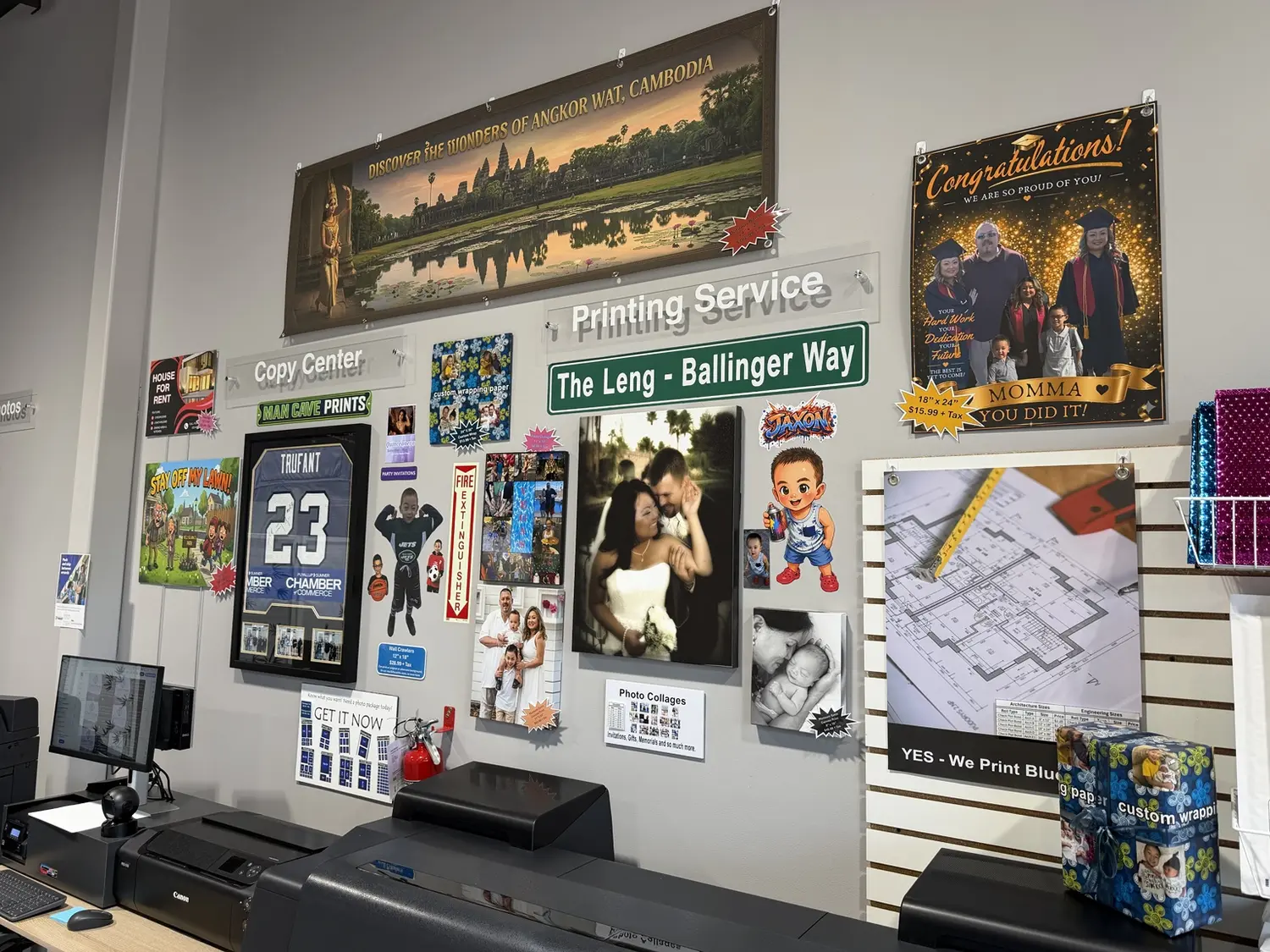 Wall of custom printing examples including signs, photo displays, and blueprints